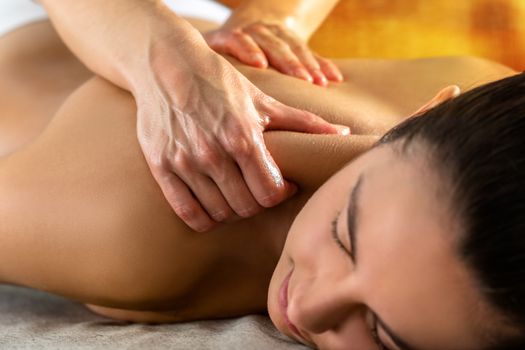 Close up of physiotherapist massaging upper neck and shoulder on young woman in spa.