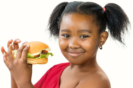 Close up portrait of cute ponytailed african girl holding appetizing hamburger.Kid smiling at camera isolated on white background. 
