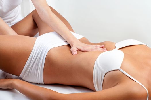 Close up of osteopath doing abdominal massage on woman.