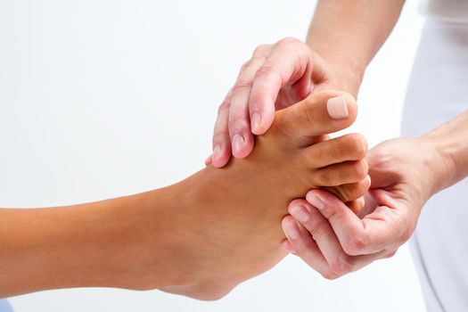 Extreme close up Therapist doing reflexology massage on human female foot. Isolated on white background.