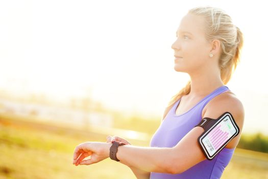 Close up portrait of attractive young woman setting workout on smart watch.Girl in sport wear with fitness chart showing on smart watch.