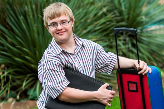 Close up portrait of young Down syndrome student with file and trolley.