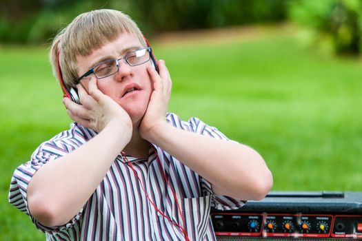 Close up portrait of handicapped boy enjoying music on head phones outdoors.
