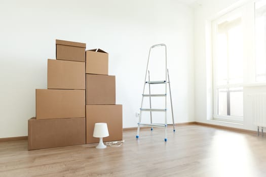 Stack of cardboard boxes for moving in interior apartment, movement or real estate concept. No people in empty room