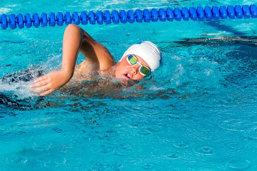 Close up action shot of teenager practicing freestyle in swimming pool.