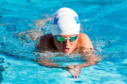 Close up action shot of young boy swimming breaststroke.