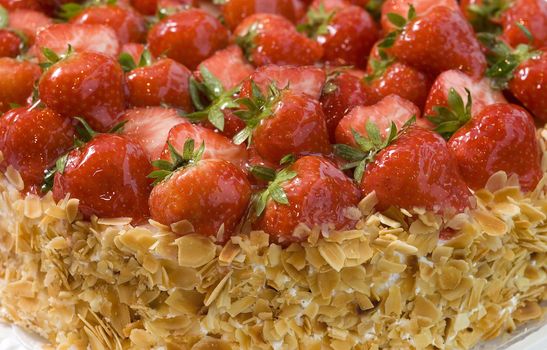 Fresh fruit cake with strawberries and sliced nuts. Close up view.