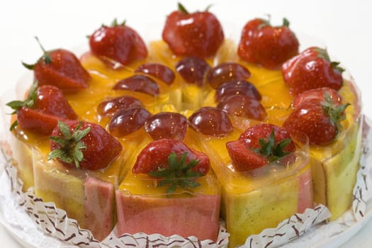 Fresh fruit cake with strawberries and plum sliced in pieces. Close up view.