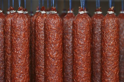 Sticks salami or sausages hanging on the ropes in the smoke house.