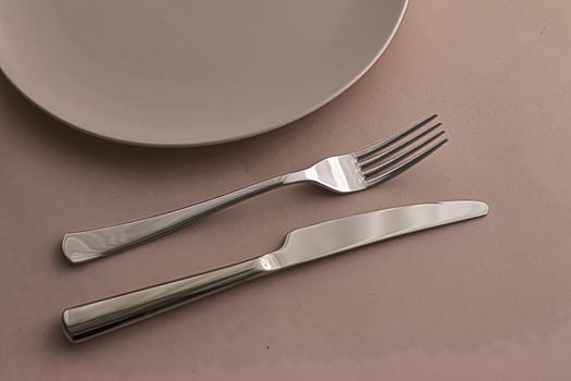 Empty plate and cutlery as mockup set on brown background, top tableware for chef table decor and menu branding design