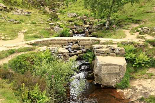 A view of Bronte Bridge across South Dean Beck near Haworth, West Yorkshire in England.  The bridge is a small clapper bridge across a stream in a valley close to Bronte Waterfall.