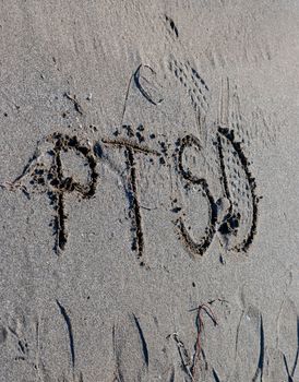 ptsd text on a beach sand, mental health concept