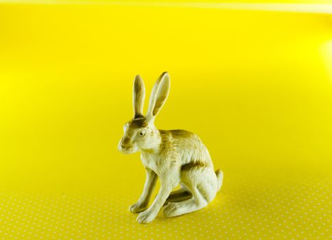 plastic figurine of a rabbit on yellow background image