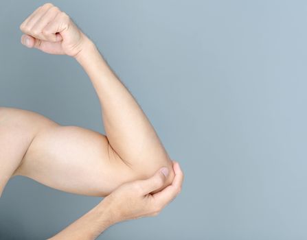 Closeup man hand holding elbow with pain on grey background, health care and medical concept