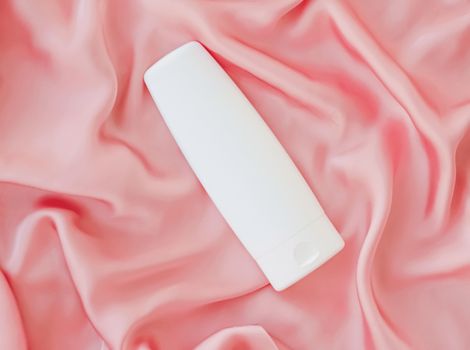Blank label cosmetic container bottle as product mockup on pink silk background, hygiene and healthcare