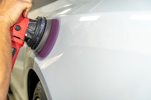 polishing the car body with a manual automatic grinder with wax and polishing paste.