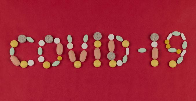 Inscription Coronavirus made from pills on a red background. Coronavirus text made of tablets. Coronavirus Protection Concept