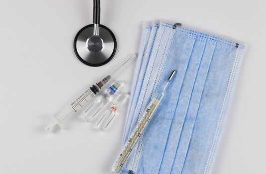 Medical protective masks on a white background with capsules, a thermometer and a stethoscope. Coronavirus Protection Concept