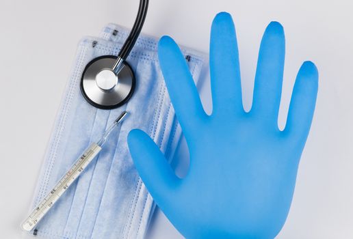 Medical mask and glove on a white background with a stethoscope and a thermometer. Coronavirus Protection Concept