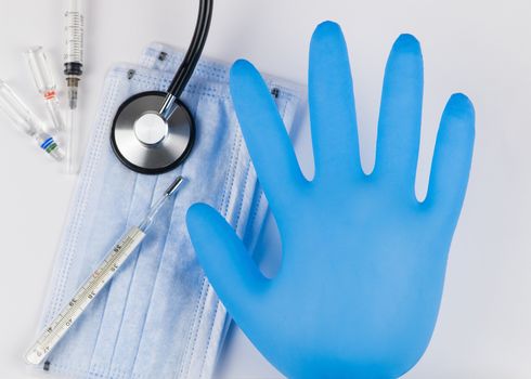 Medical mask and gloves on a white background with a stethoscope and syringe. Coronavirus Protection Concept