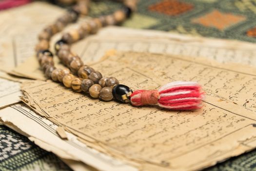 Muslim prayer beads with ancient pages from the Koran. Islamic and Muslim concepts. Ancient old sheets of paper from the Arabic book