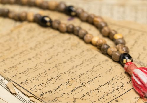 Muslim prayer beads with ancient pages from the Koran. Islamic and Muslim concepts. Ancient old sheets of paper from the Arabic book