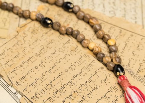 Muslim prayer beads with ancient pages from the Koran. Islamic and Muslim concepts. Ancient old sheets of paper from the Arabic book