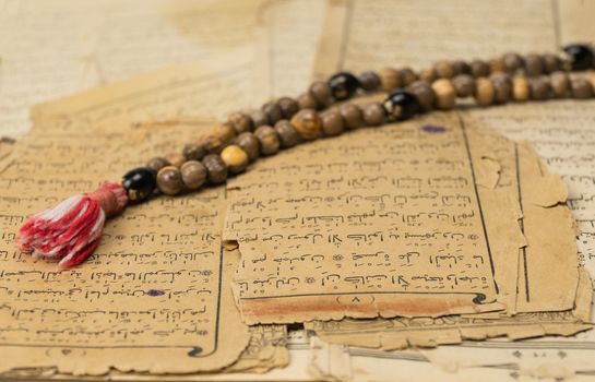 Muslim prayer beads with ancient pages from the Koran. Islamic and Muslim concepts. Ancient old sheets of paper from the Arabic book