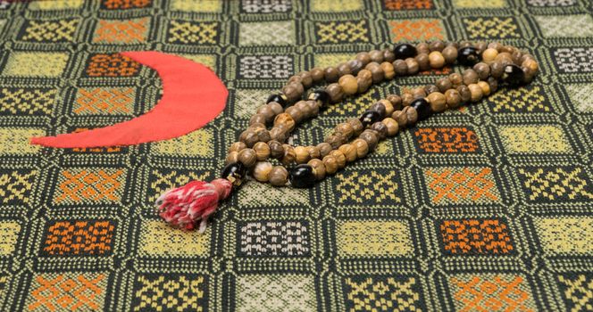 Muslim prayer beads on the prayer Mat with the Crescent symbol. Islamic and Muslim concepts