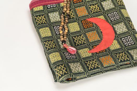 Muslim prayer beads on the prayer Mat with the Crescent symbol on а white background. Islamic and Muslim concepts