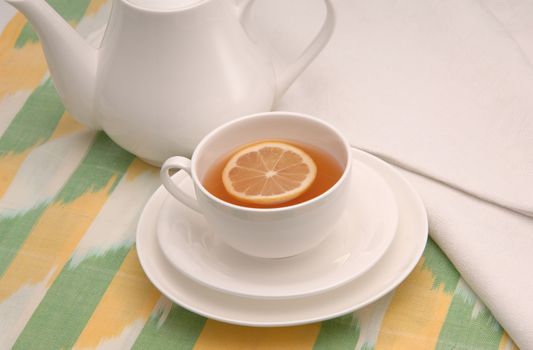 on a napkin cup of tea with lemon in a saucer and teapot