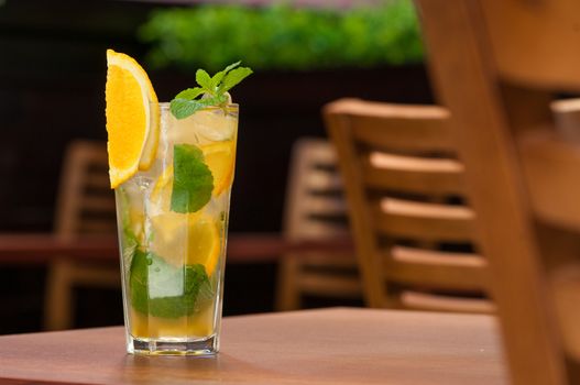 a cold drink with a yellow citrus on the table in a glass