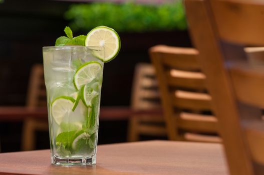 a cold drink with green citrus fruit on a table in a glass