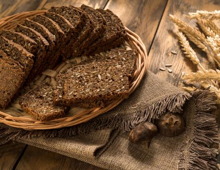 bread in a wicker tray with a napkin and spikelets on wooden surface