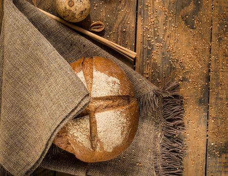 round loaf of bread on a cloth napkin and wooden boards with crumbs