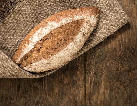 a loaf of bread on a cloth napkin and wooden boards, top view