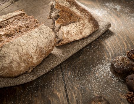 cracked a loaf of bread on a cloth napkin and wooden boards