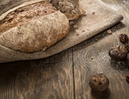 the broken loaf of bread on a cloth napkin and wooden boards