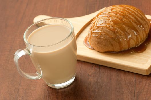 bread drizzled with honey on a wooden plate and a glass of milkshake