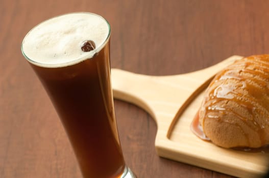 bread drizzled with honey on a wooden plate and a glass of cocktail with berries