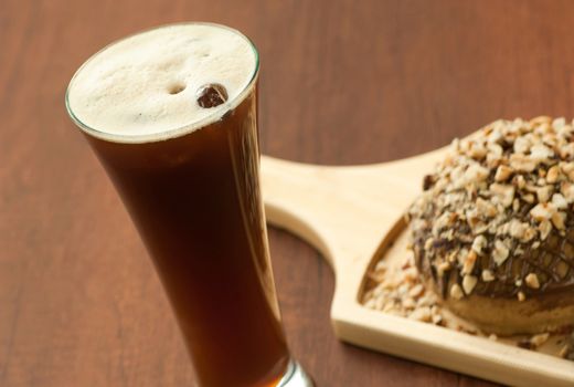 bread garnished with nuts on a wooden plate and a glass of cocktail with berries