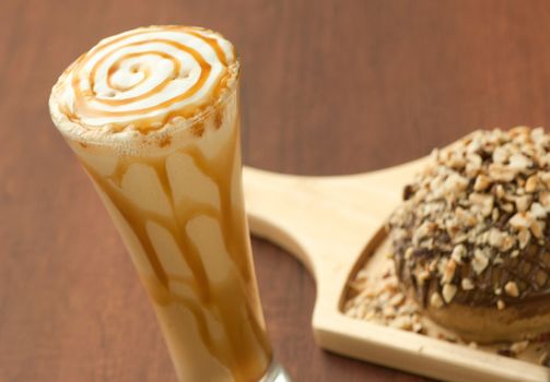 bread garnished with nuts on a wooden plate and a glass of milkshake