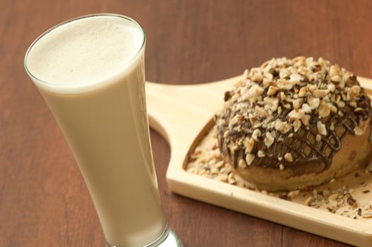 bread garnished with nuts on a wooden plate and a glass of milkshake