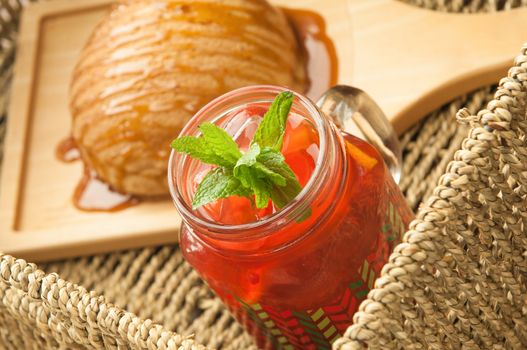 bread drizzled with honey on a wooden plate and a glass with a cocktail in a wicker basket