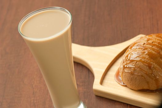 bread drizzled with honey on a wooden plate and a glass of milkshake