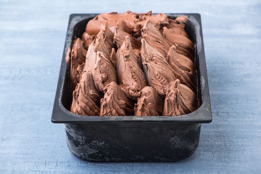 appetizing ice cream in a plastic container on a decorative blue background