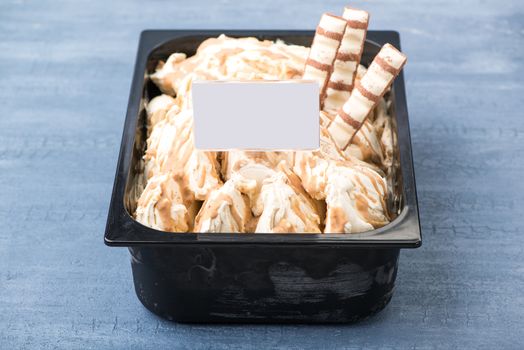 appetizing ice cream in a plastic container with a price tag on a decorative blue background