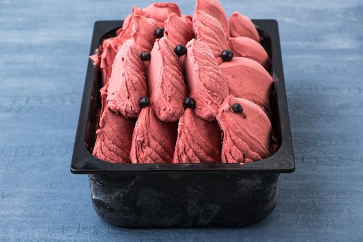 appetizing ice cream in a plastic container on a decorative blue background