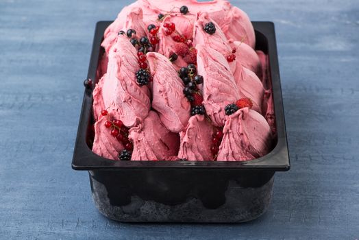 appetizing ice cream in a plastic container on a decorative blue background