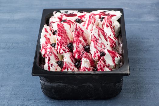 appetizing ice cream in a plastic container on a decorative blue background